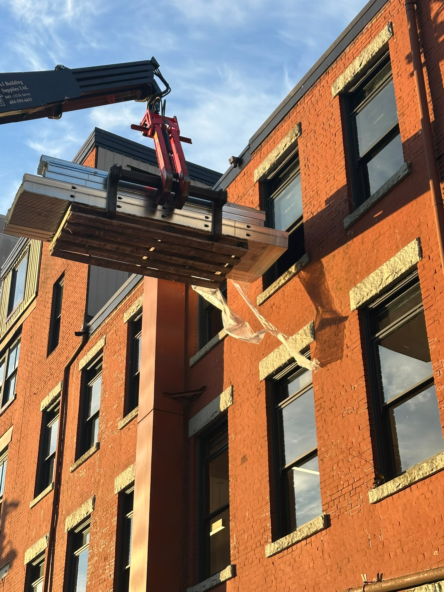 Enduro Construction — articulating crane lifting a steel-stud bundle